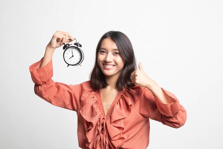 Young Asian woman show thumbs up with a clock on white backgroundの写真素材