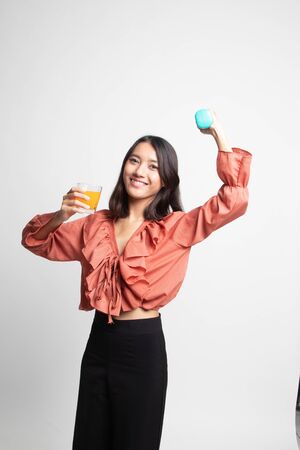 Young Asian woman with dumbbell drink orange juice on white backgroundの写真素材
