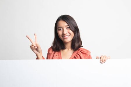 Young Asian woman show victory sign with blank sign on white backgroundの写真素材