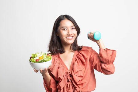 Healthy Asian woman with dumbbells and salad on white backgroundの写真素材