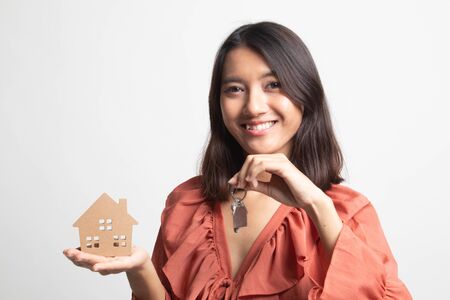 Happy young asian woman with house model and key on white backgroundの写真素材