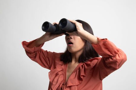 Young Asian woman with binoculars on white backgroundの写真素材