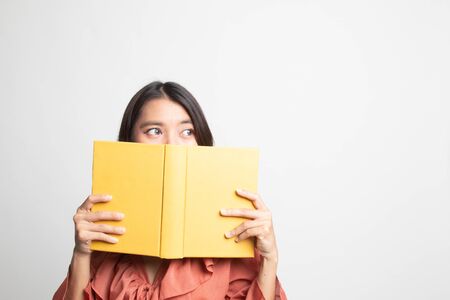 Young Asian woman with a book cover her face on white backgroundの写真素材