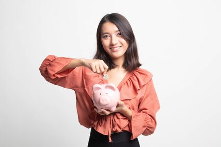 Asian woman with coin and pig coin bank on white backgroundの写真素材