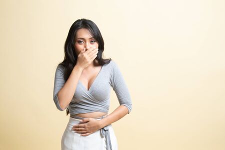 Young Asian woman got stomachache about to vomit   on beige backgroundの写真素材