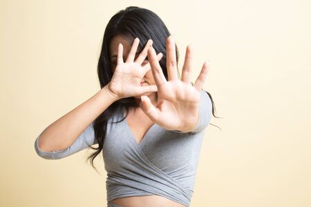 Young Asian woman hide her  face   on beige backgroundの写真素材