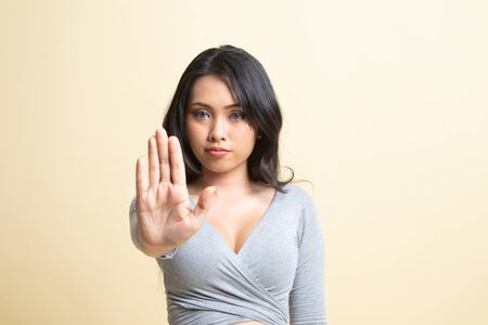 Portrait of an asian woman showing stop gesture   on beige backgroundの写真素材