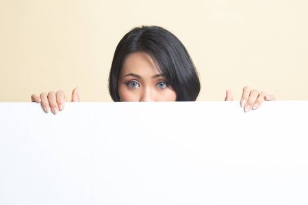 Close up of young Asian woman behind a blank sign   on beige backgroundの写真素材