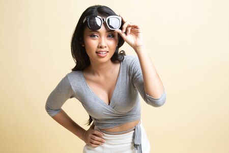 Portrait of a beautiful young asian girl in sunglasses   on beige backgroundの写真素材