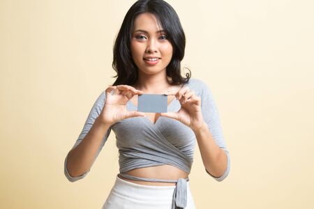 Young Asian woman smile with blank card   on beige backgroundの写真素材