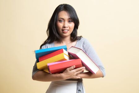 Young Asian woman studying  with may books   on beige backgroundの写真素材
