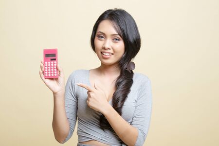 Asian woman point to  calculator   on beige backgroundの写真素材