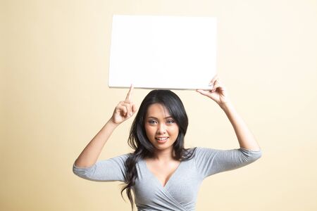 Young Asian woman point to blank sign   on beige backgroundの写真素材