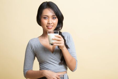 Healthy Asian woman drinking a glass of milk   on beige background