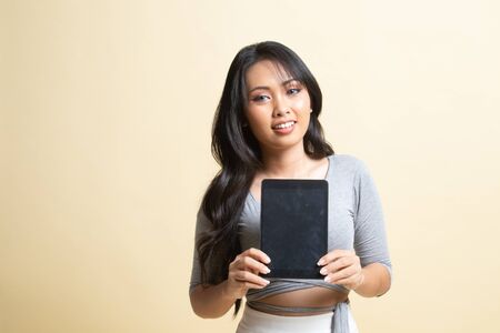 Young Asian woman with a computer tablet   on beige backgroundの写真素材