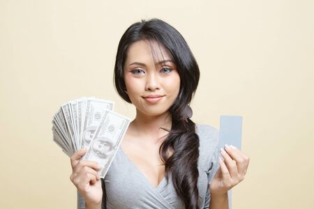 Portrait of  young asian woman  showing bunch of money banknotes   on beige backgroundの写真素材