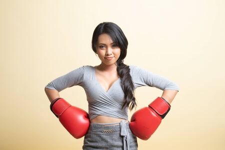 Young Asian woman with red boxing gloves   on beige backgroundの写真素材