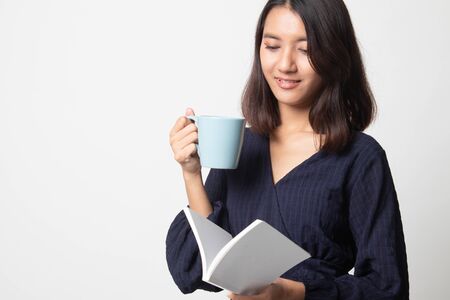 Young Asian woman with a book and cup of coffee on white backgroundの写真素材