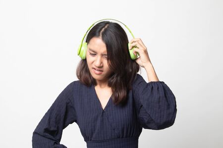 Too loud.  portrait of  young asian woman  holding  headphones and making unhappy face on white backgroundの写真素材