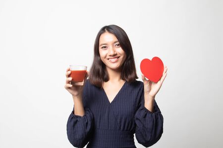 Young Asian woman with tomato juice and red heart on white backgroundの写真素材