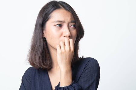 Unsure hesitant nervous young asian  woman biting her fingernails on white backgroundの写真素材