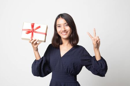 Young Asian woman show Victory sign with a gift box on white backgroundの写真素材
