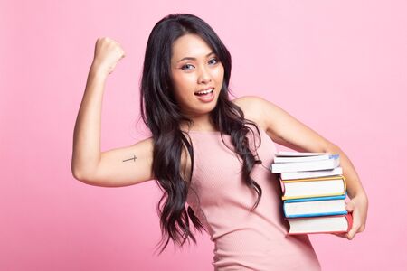 Young Asian woman studying  with may books on pink backgroundの写真素材