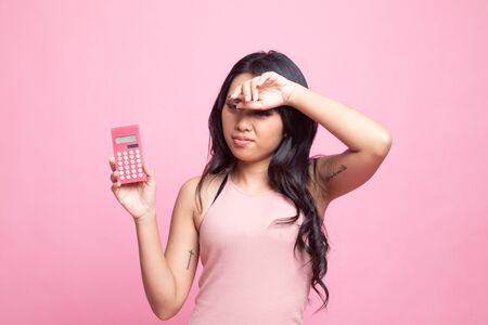Asian woman got  headache with calculator on pink backgroundの写真素材