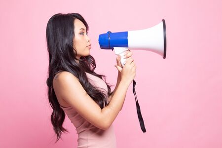 Beautiful young Asian woman announce with megaphone on pink backgroundの写真素材