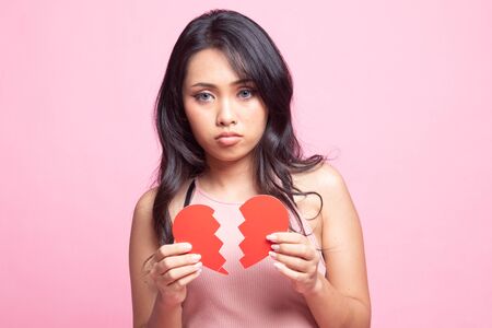 Beautiful young Asian woman with broken heart on pink backgroundの写真素材