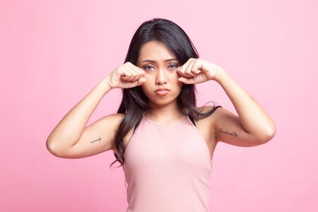 Young Asian woman sad and cry on pink backgroundの写真素材