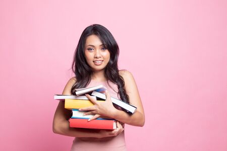 Young Asian woman studying  with may books on pink backgroundの写真素材