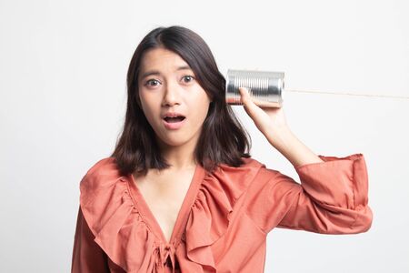Surprised young Asian woman with tin can phone on white backgroundの写真素材