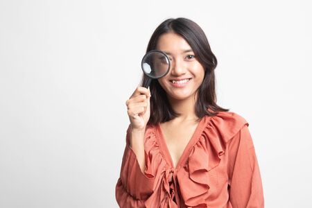 Young Asian woman with a magnifying glass on white backgroundの写真素材
