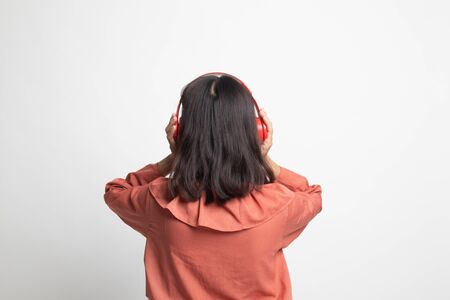 Pretty asian girl listening music with her headphones on white backgroundの写真素材