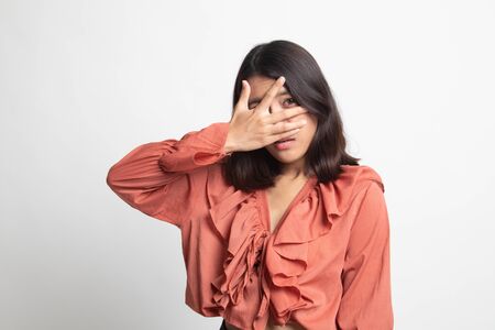 Beautiful young Asian woman peeking through fingers on white backgroundの写真素材