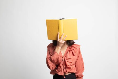 Young Asian woman with a book cover her face on white backgroundの写真素材