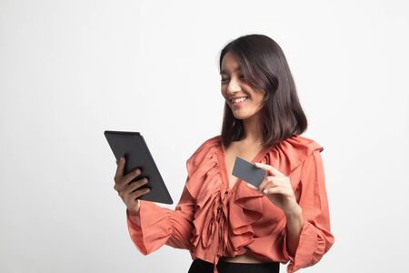 Young Asian woman is shopping online with credit card and tablet on white backgroundの写真素材
