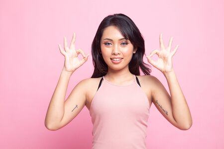 Asian woman show double OK hand sign  and smile on pink backgroundの写真素材