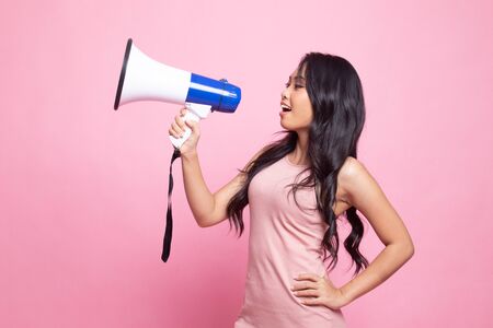 Beautiful young Asian woman announce with megaphone on pink backgroundの写真素材