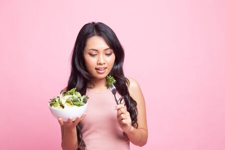 Healthy Asian woman with salad on pink backgroundの写真素材