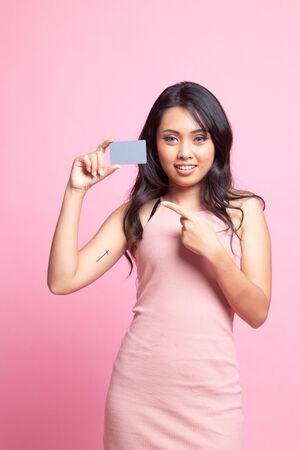 Young Asian woman point to a blank card on pink backgroundの写真素材