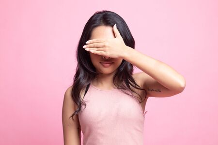 Young Asian woman close her eyes with hand on pink backgroundの写真素材