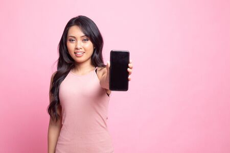 Young Asian woman with mobile phone on pink backgroundの写真素材