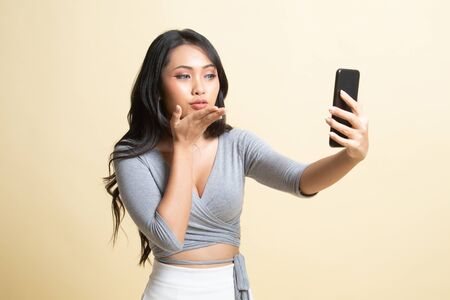 Young Asian woman with mobile phone   on beige backgroundの写真素材