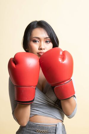 Young Asian woman with red boxing gloves   on beige backgroundの写真素材