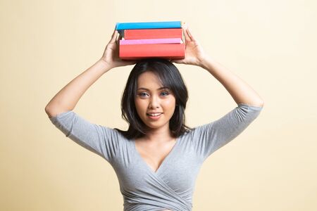 Young Asian woman studying  with may books   on beige backgroundの写真素材