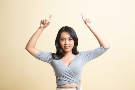 Young Asian woman point to blank space   on beige backgroundの写真素材