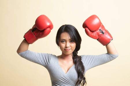 Young Asian woman with red boxing gloves   on beige backgroundの写真素材