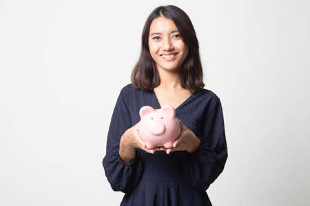 Young Asian woman with a pig coin bank on white backgroundの写真素材